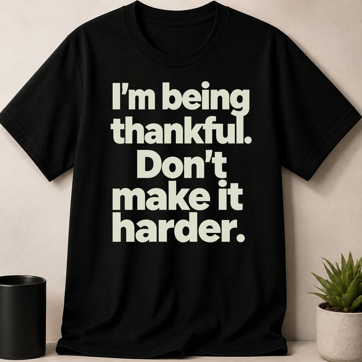Black t-shirt with cream text that reads "I'm being thankful. Don't make it harder."