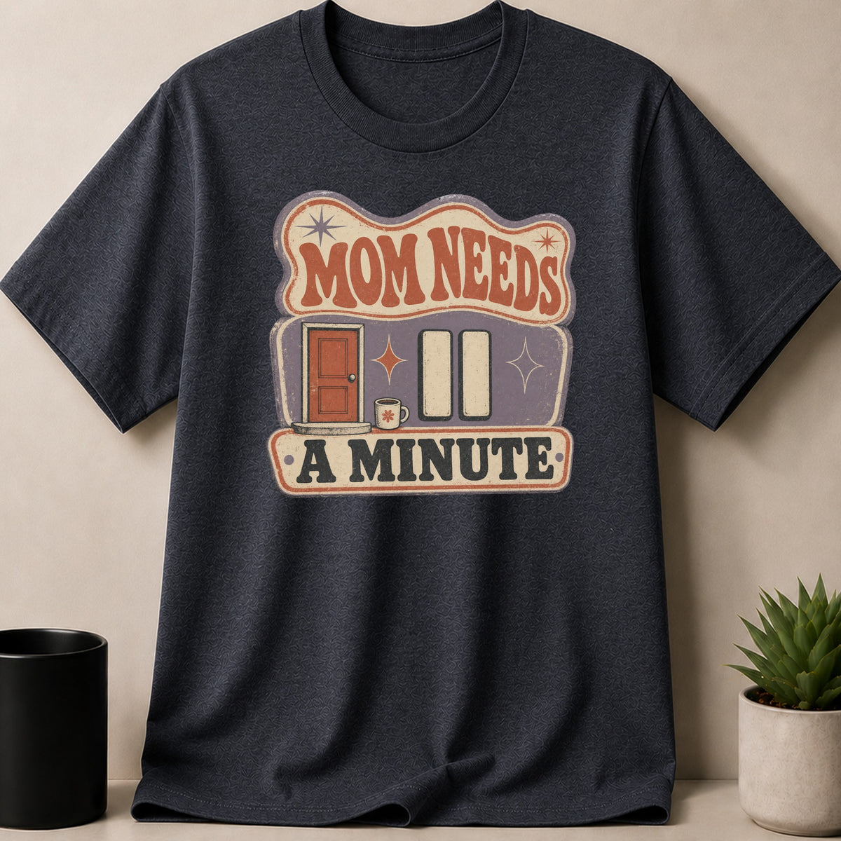 Dark gray t-shirt with "Mom Needs A Minute" graphic featuring a door and coffee mug.