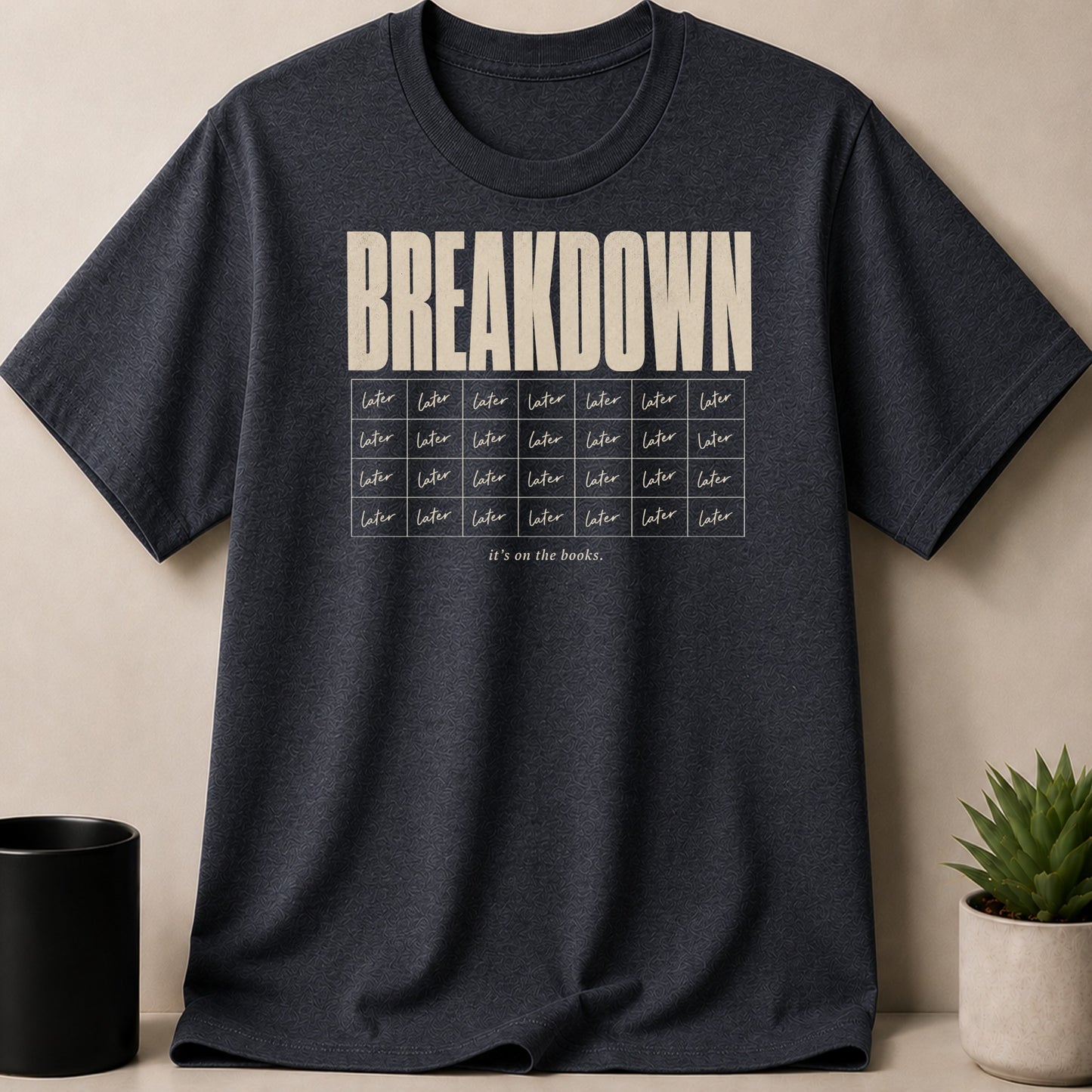 Dark t-shirt with "BREAKDOWN" and "it's on the books." text.