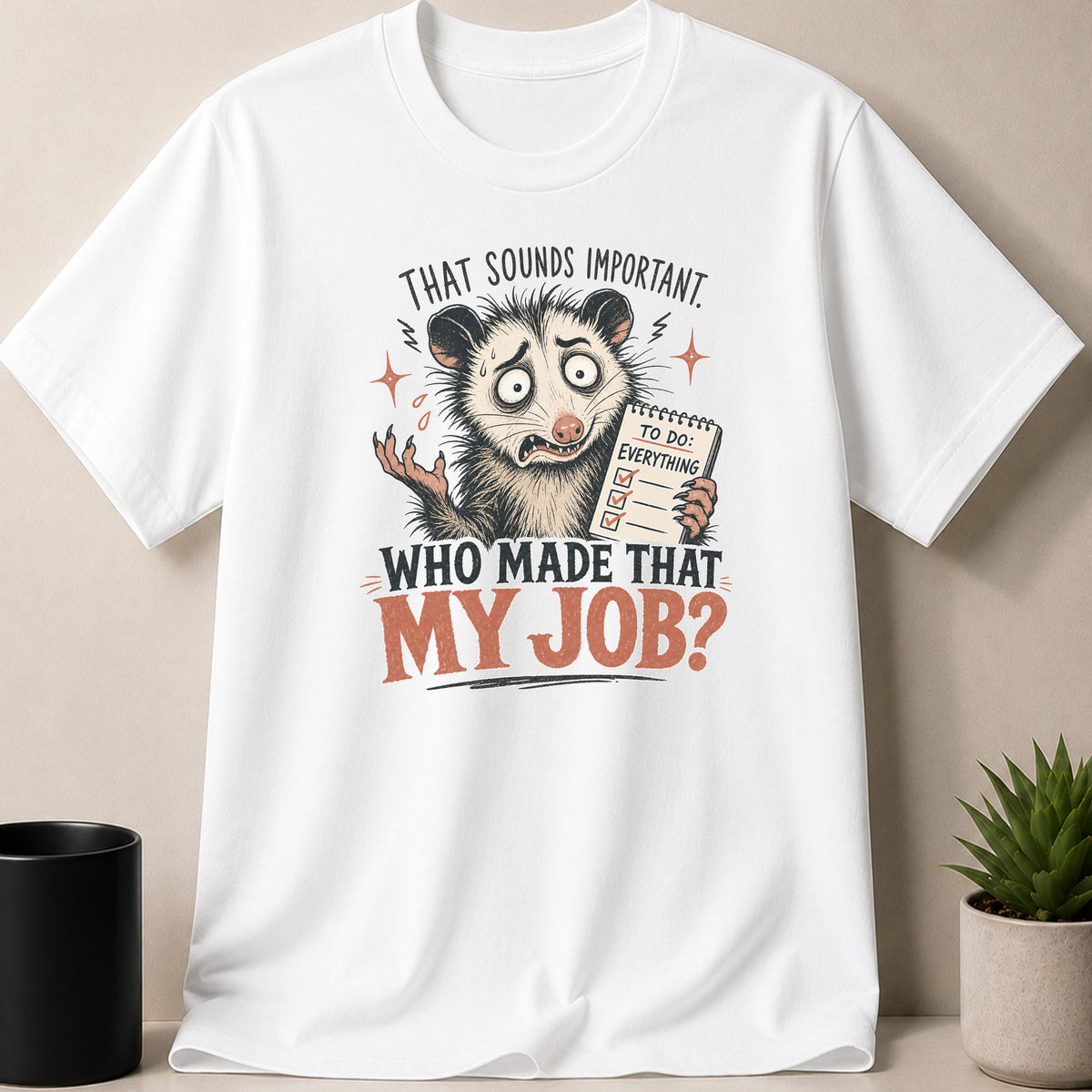 White t-shirt with a stressed opossum holding a checklist and the text "Who Made That My Job?".