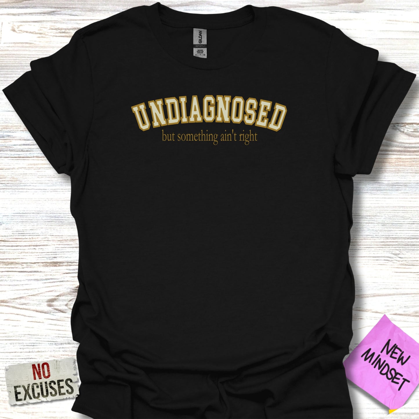 Black t-shirt with "UNDIAGNOSED but something ain't right" in gold text.