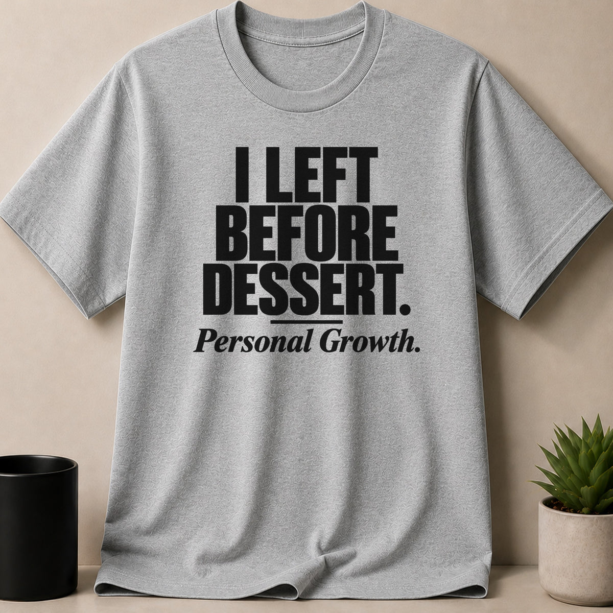 Gray short-sleeve t-shirt with bold black text reading "I LEFT BEFORE DESSERT. Personal Growth."