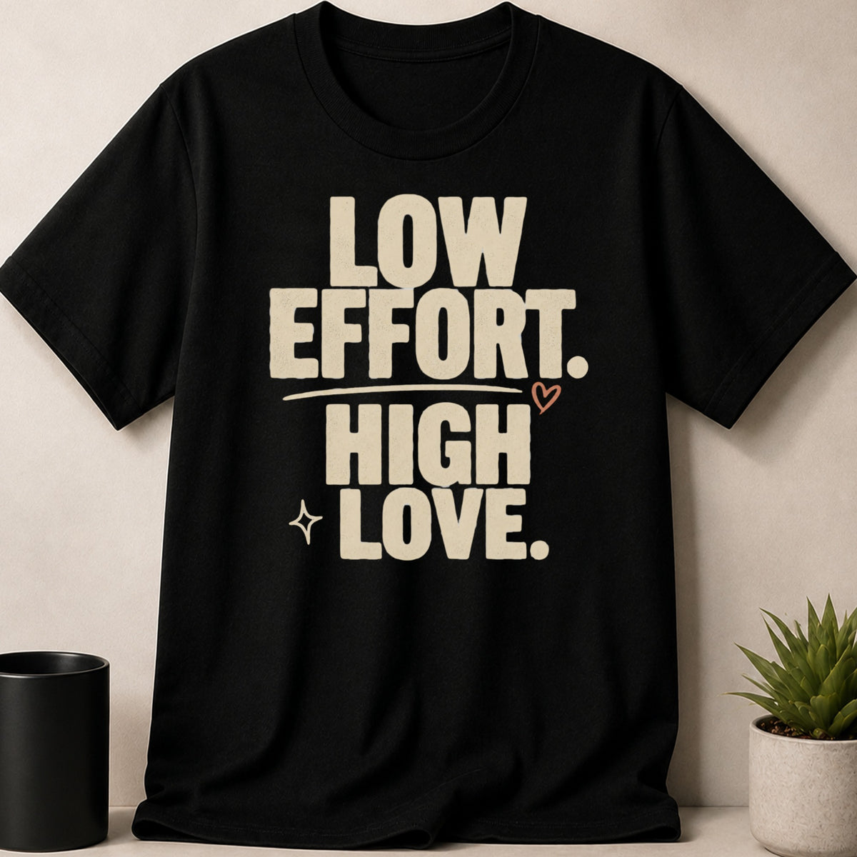 Black t-shirt with cream text "LOW EFFORT. HIGH LOVE." and small heart graphic.