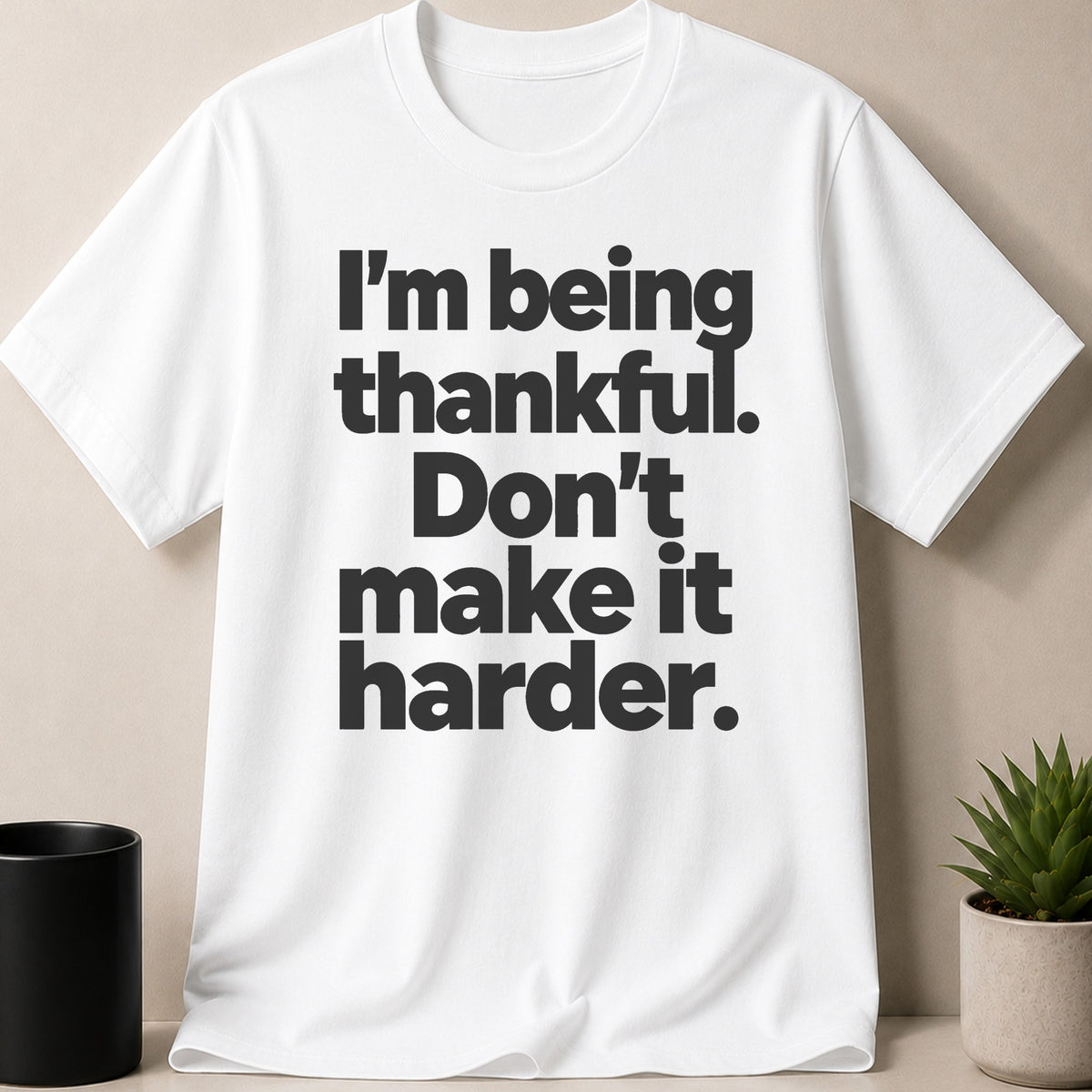 White t-shirt with black text reading "I'm being thankful. Don't make it harder."