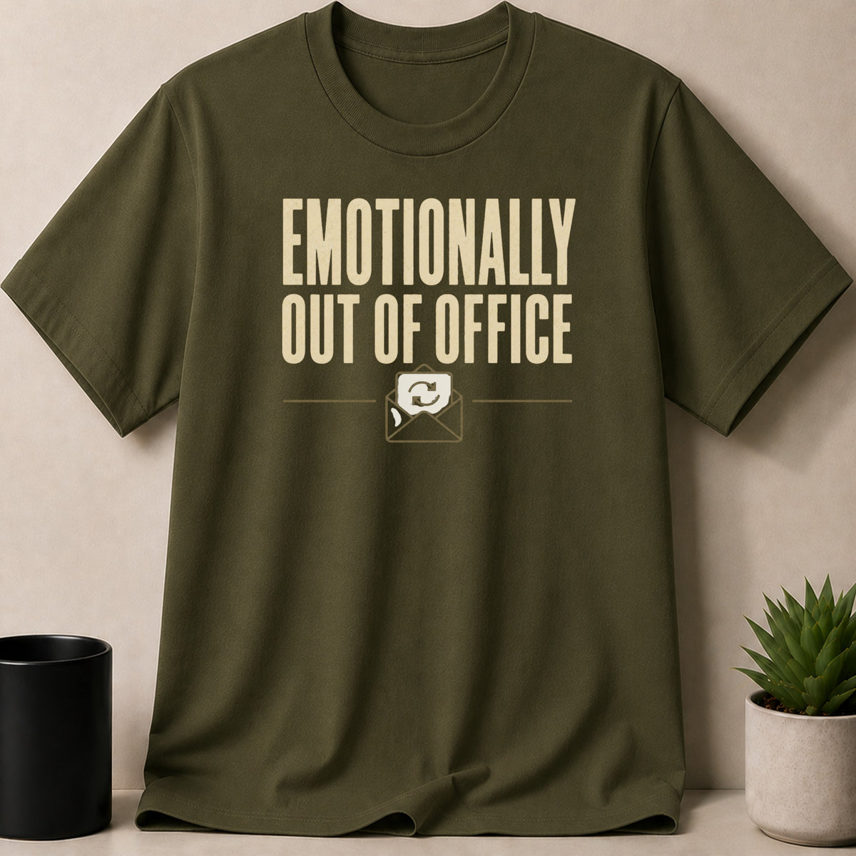 Olive green t-shirt with "EMOTIONALLY OUT OF OFFICE" text and an envelope icon.