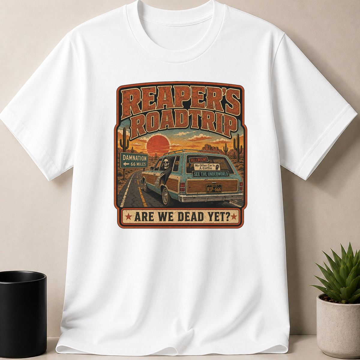 White t-shirt — Reaper's Roadtrip graphic with skeleton driving a station wagon, "Damnation 66 Miles" and "Are We Dead Yet?".