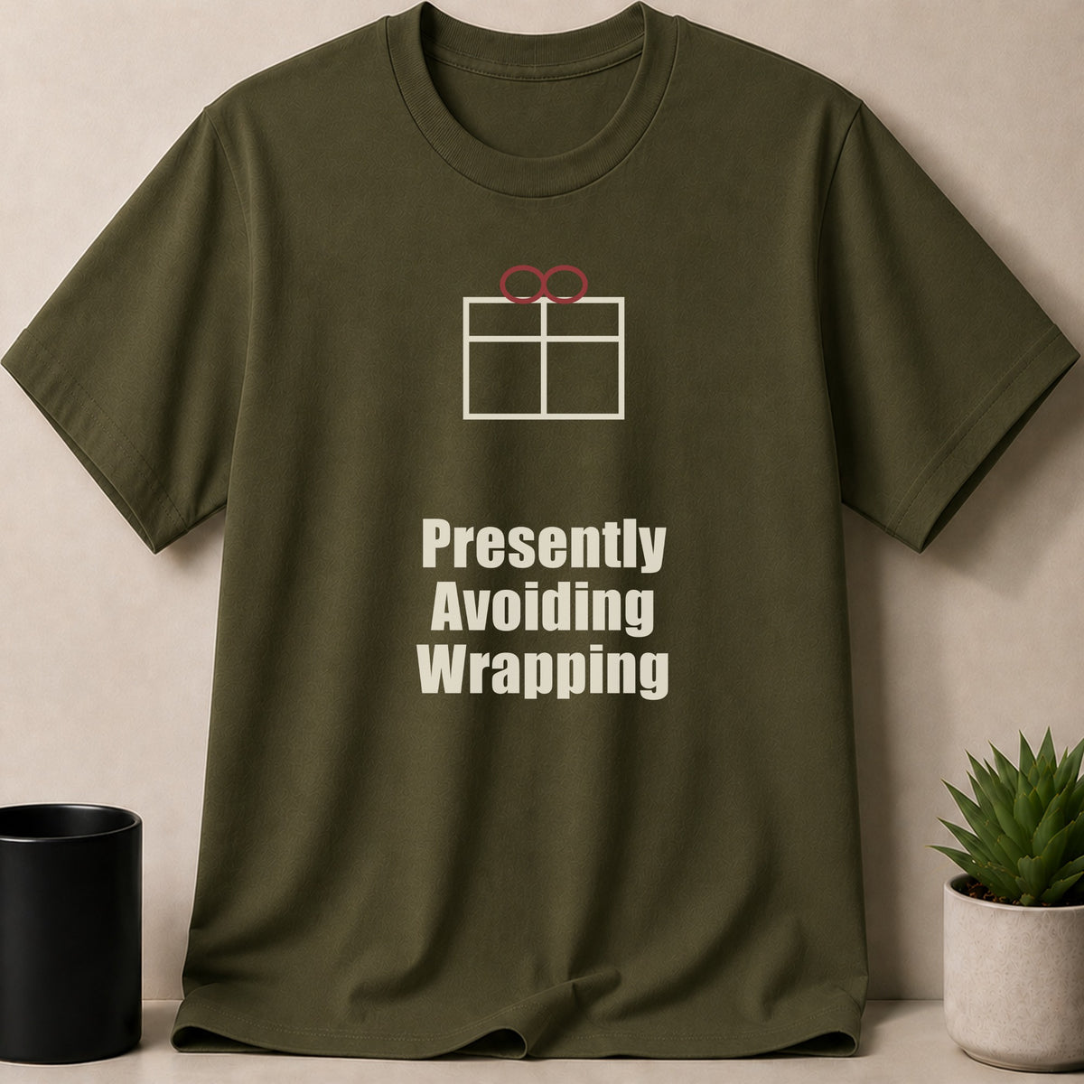 An olive green t-shirt with a gift box graphic and the text Presently Avoiding Wrapping.