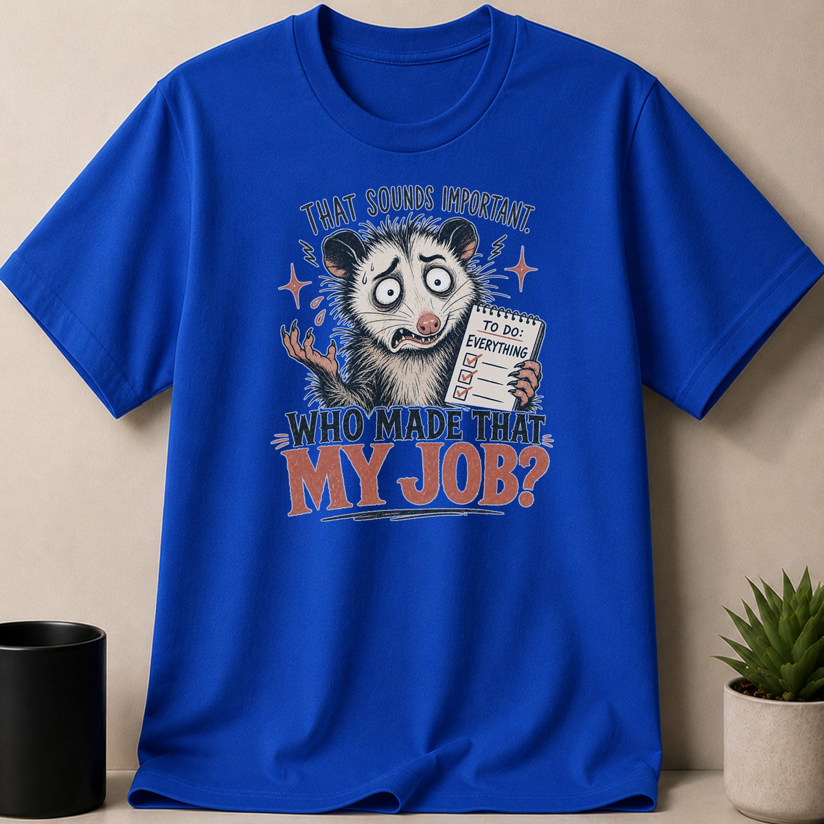 Blue t-shirt with an opossum graphic that says "That sounds important. To do: Everything. Who made that my job?"