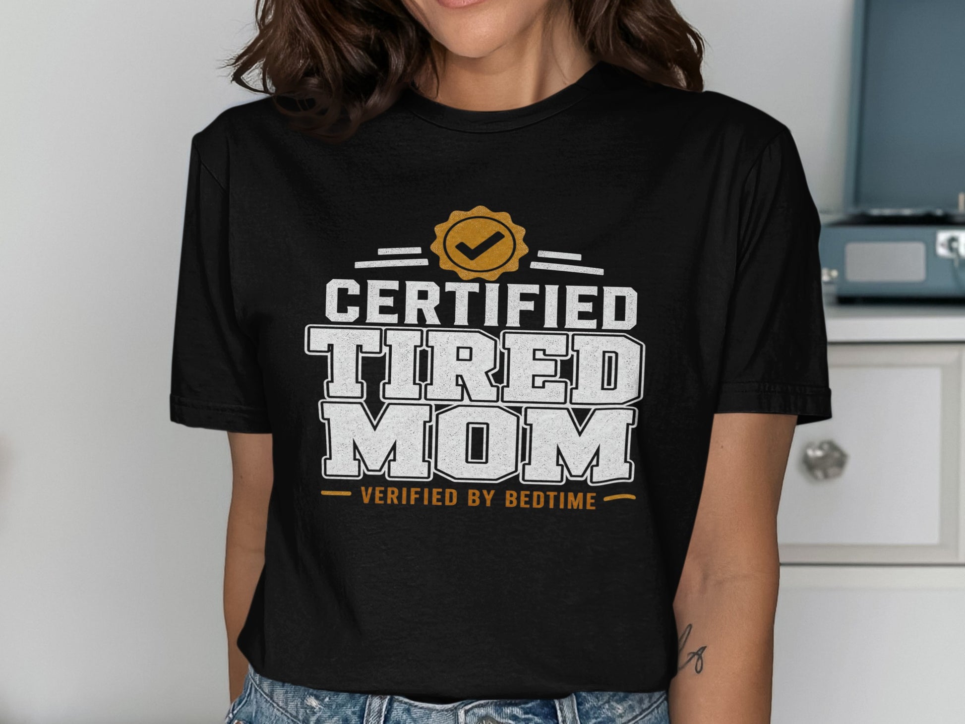 Black t-shirt with "Certified Tired Mom Verified by Bedtime" text.