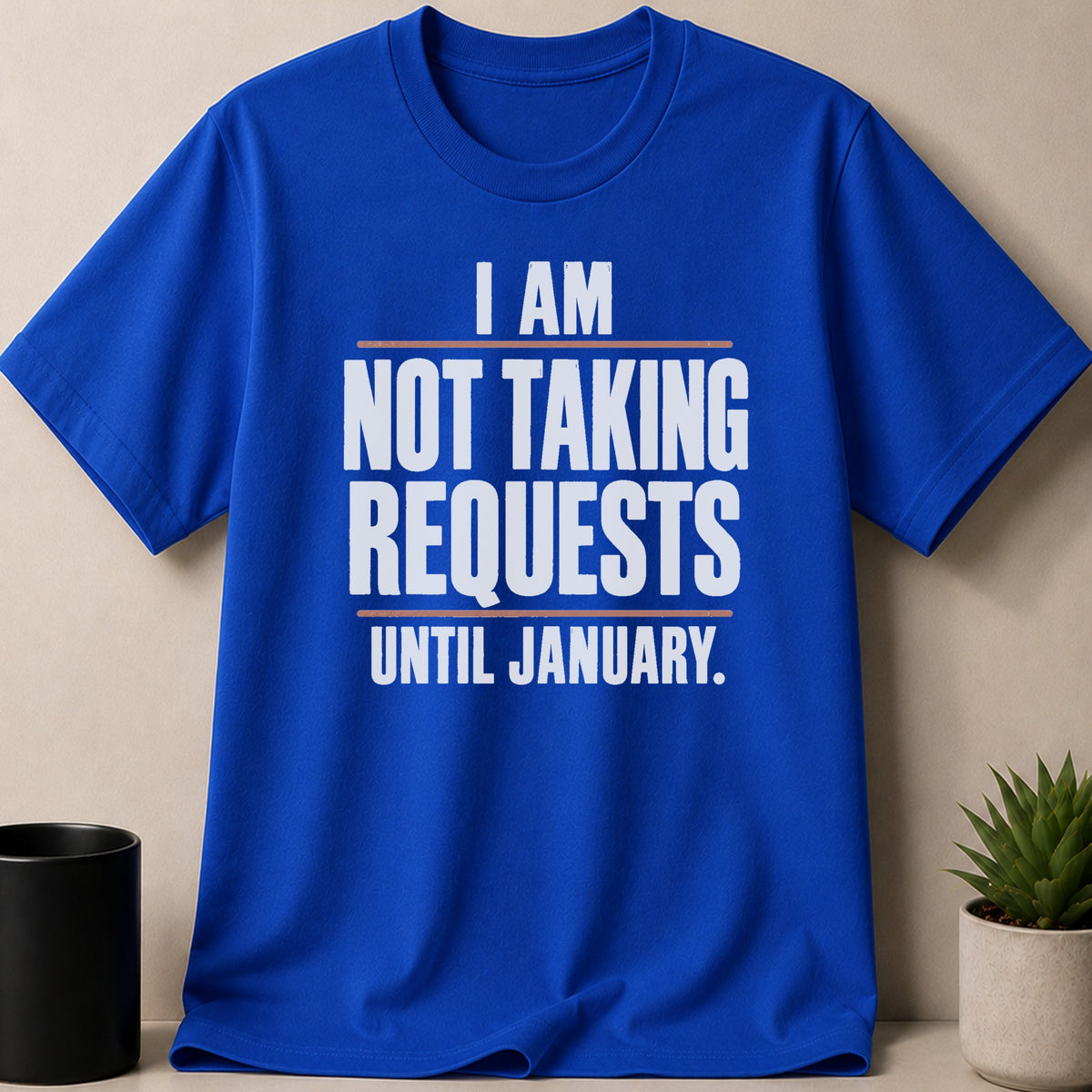 A blue short-sleeve t-shirt with the white text "I AM NOT TAKING REQUESTS UNTIL JANUARY." printed on the chest.