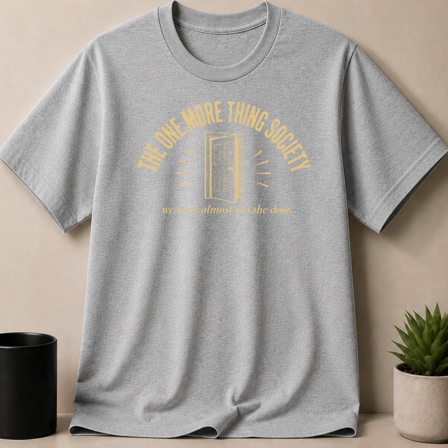 Grey t-shirt with yellow text and a door graphic reading "THE ONE MORE THING SOCIETY."