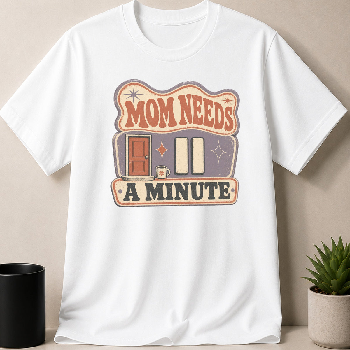 White t-shirt with "Mom Needs A Minute" graphic featuring a door and pause button.
