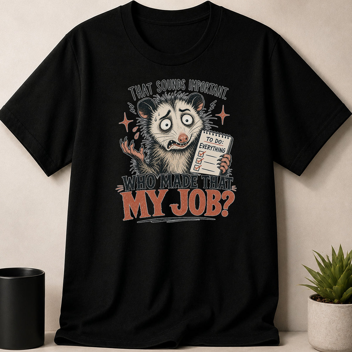 Black t-shirt with opossum holding a to-do list reading "EVERYTHING" and text "WHO MADE THAT MY JOB?".