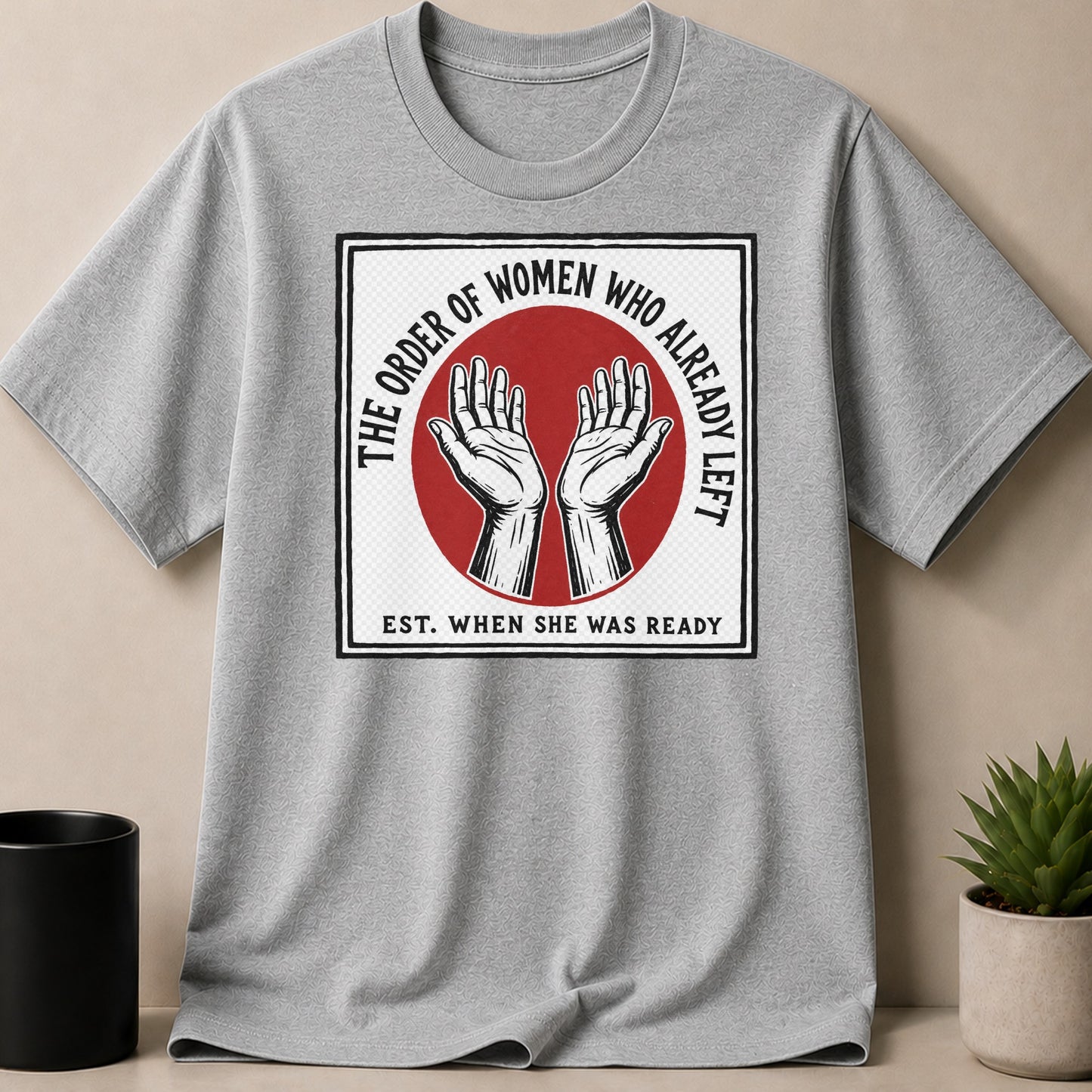 Grey t-shirt with white square graphic featuring hands, red circle, and text.