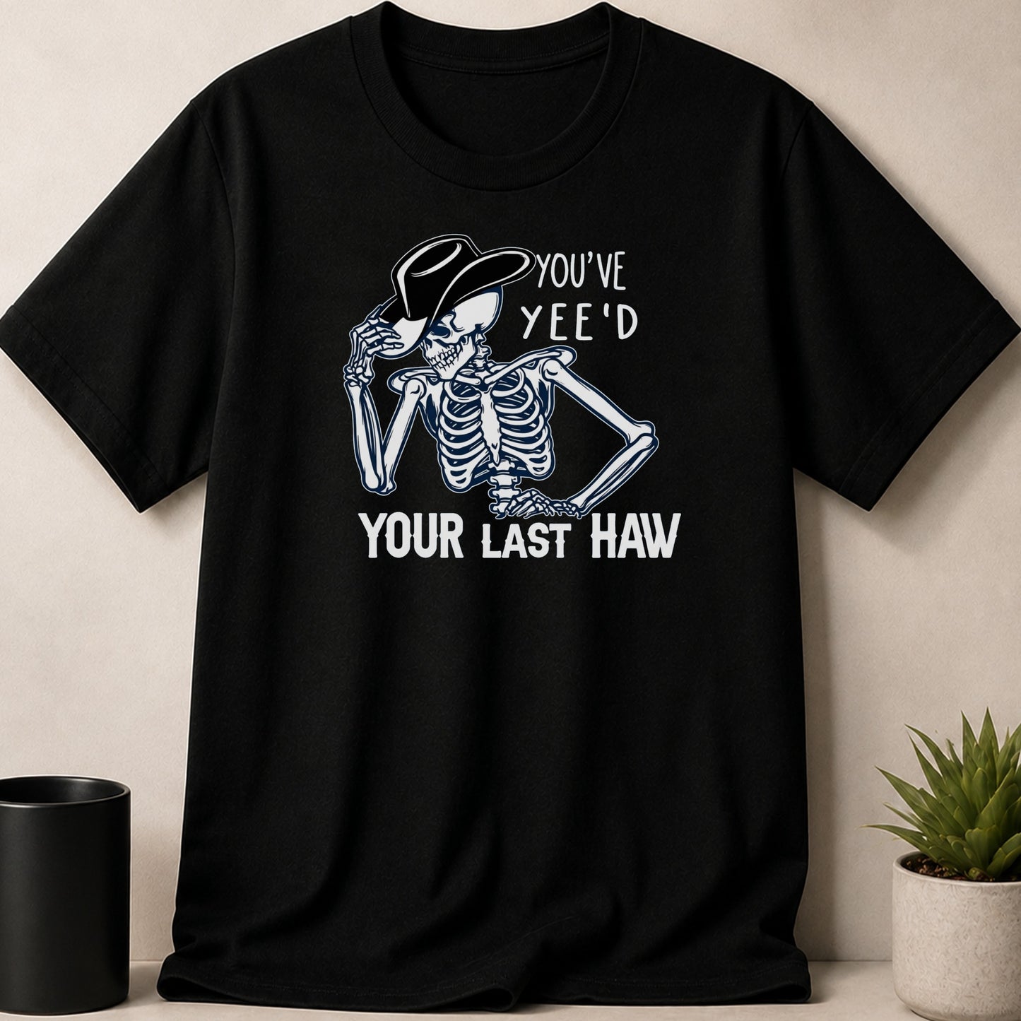 Black t-shirt with a skeleton wearing a cowboy hat and the text "YOU'VE YEE'D YOUR LAST HAW".