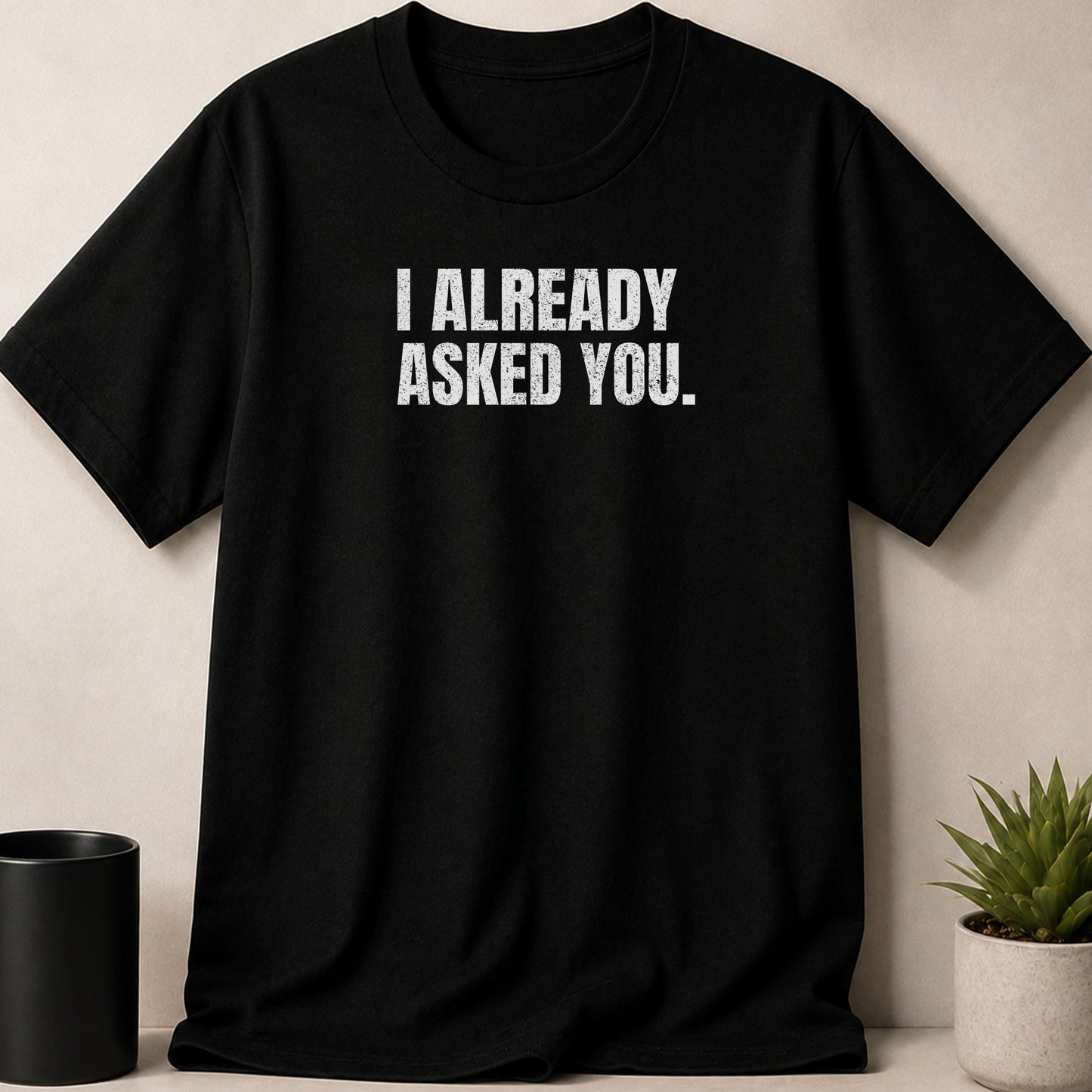 Black t-shirt with white distressed text reading "I ALREADY ASKED YOU."