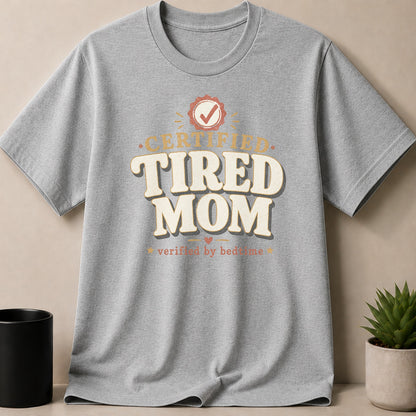 Gray t-shirt with "Certified Tired Mom verified by bedtime" text and a checkmark emblem.