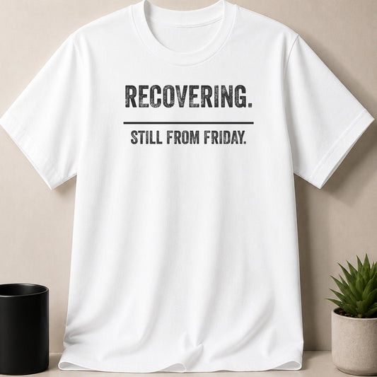 A white short-sleeved t-shirt with the black text RECOVERING. STILL FROM FRIDAY. displayed centrally on the chest.