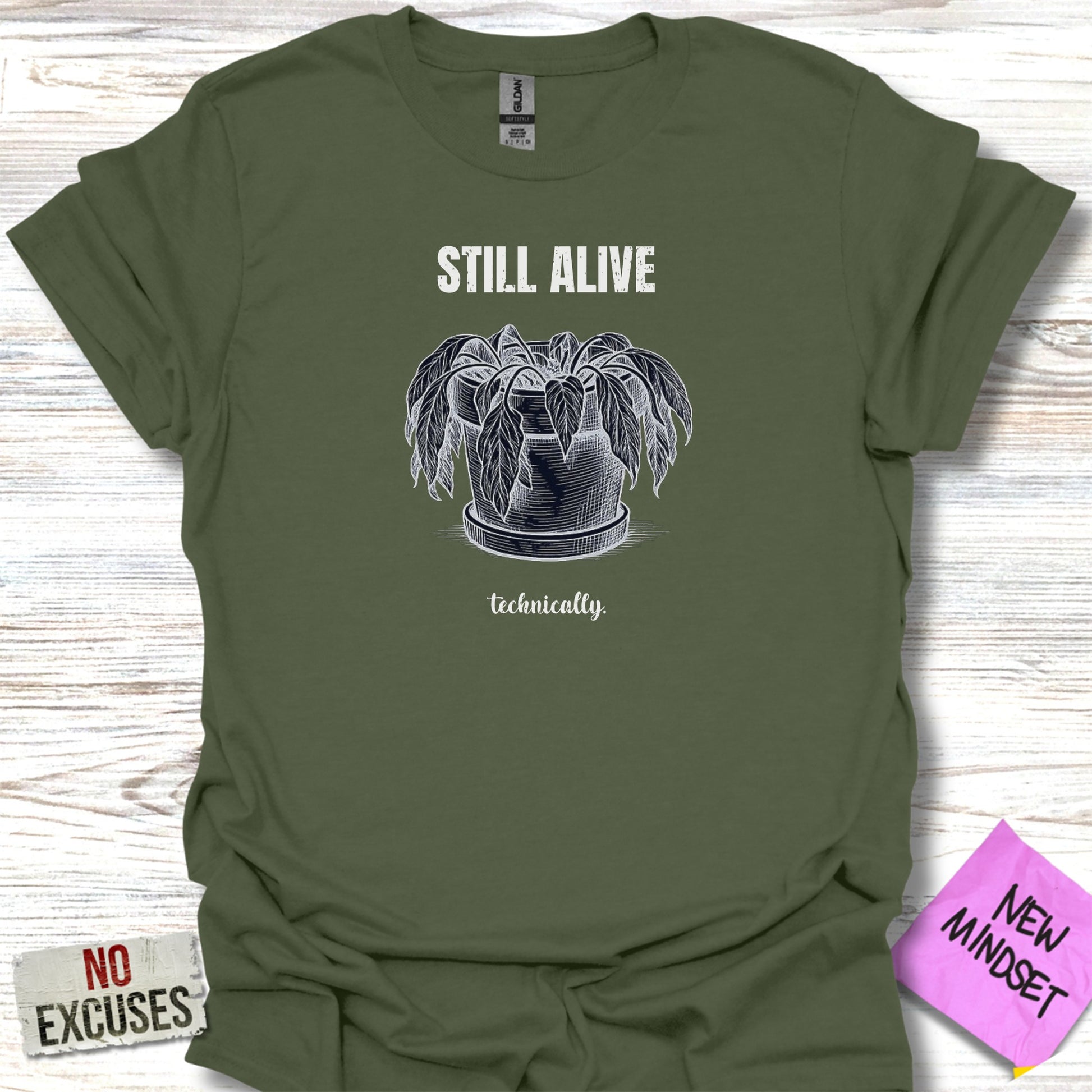 Green t-shirt with a potted plant and the text "STILL ALIVE technically."