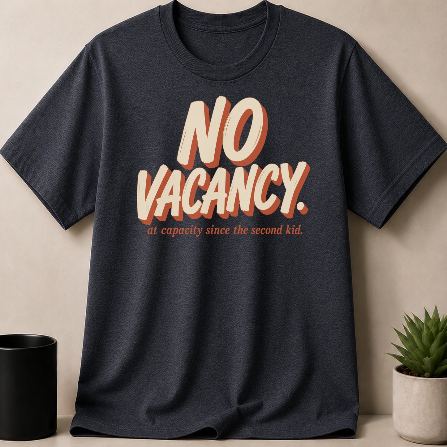 Dark t-shirt with "NO VACANCY. at capacity since the second kid." text.