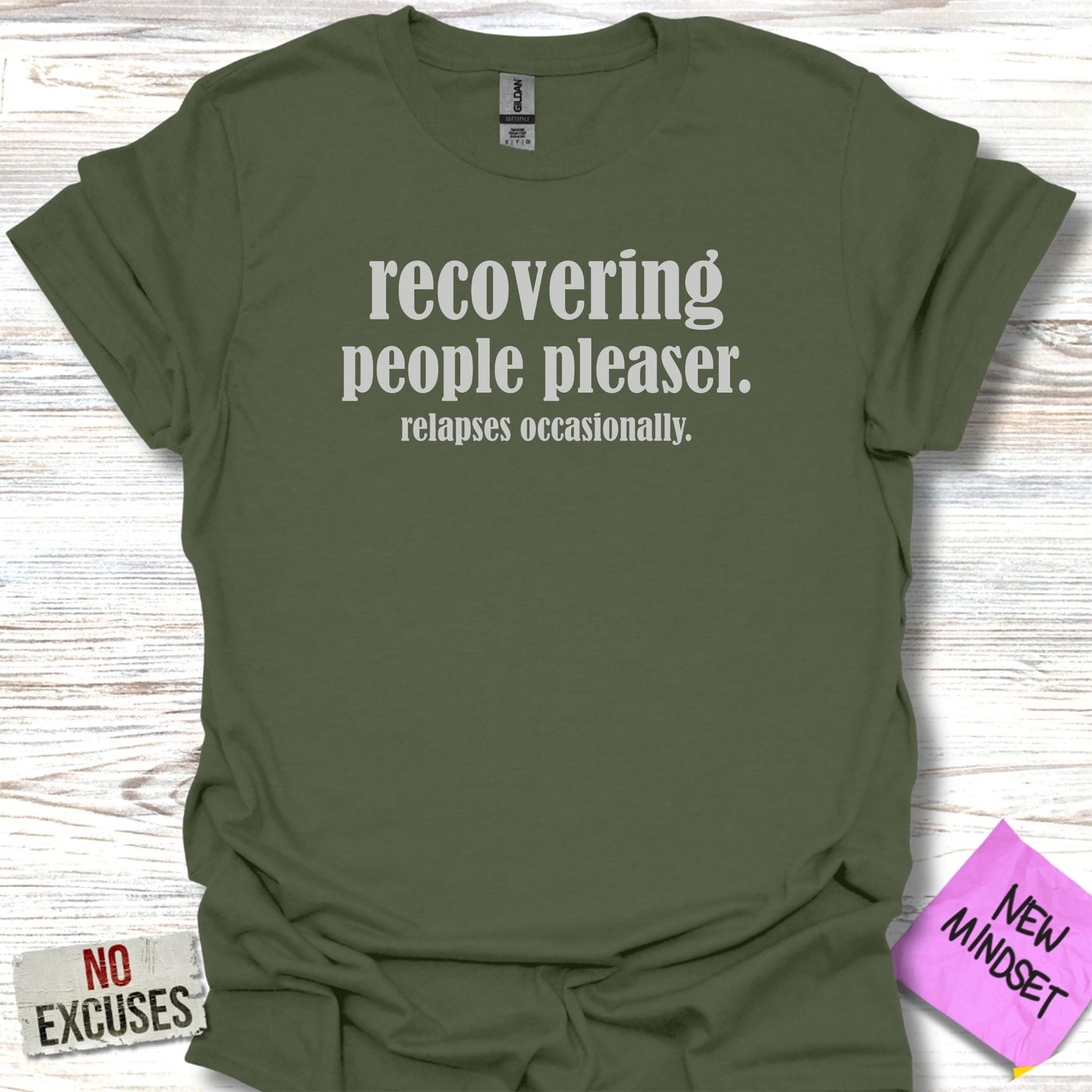 Olive green t-shirt with "RECOVERING people pleaser. relapses occasionally." text.