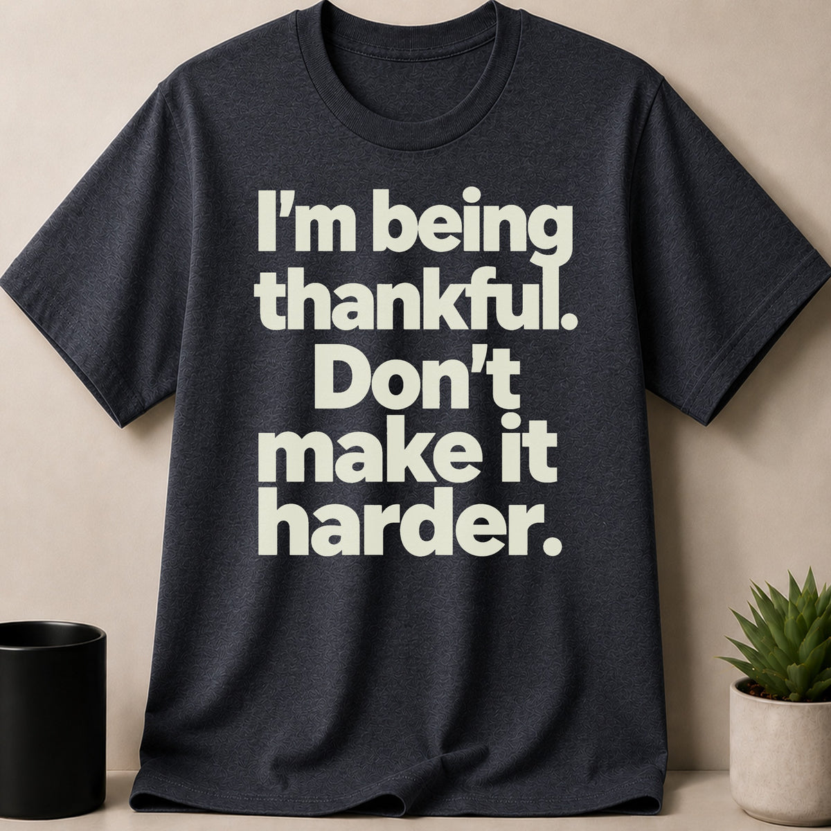 Dark gray t-shirt with cream text reading "I'm being thankful. Don't make it harder."