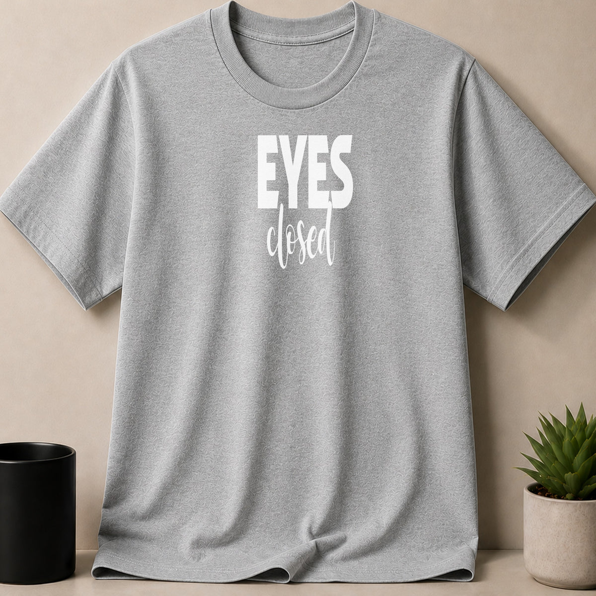 Gray t-shirt with "EYES closed" text and subtle patterned fabric.