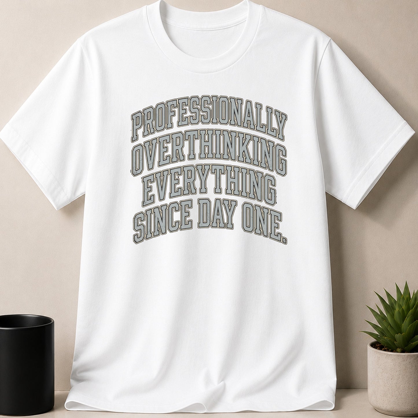 White t-shirt with "Professionally Overthinking Everything Since Day One" in grey text.