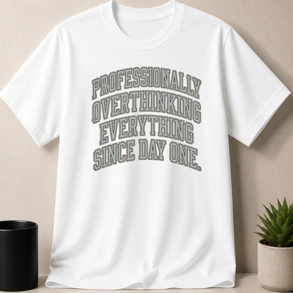 White t-shirt with "Professionally Overthinking Everything Since Day One" in grey text.