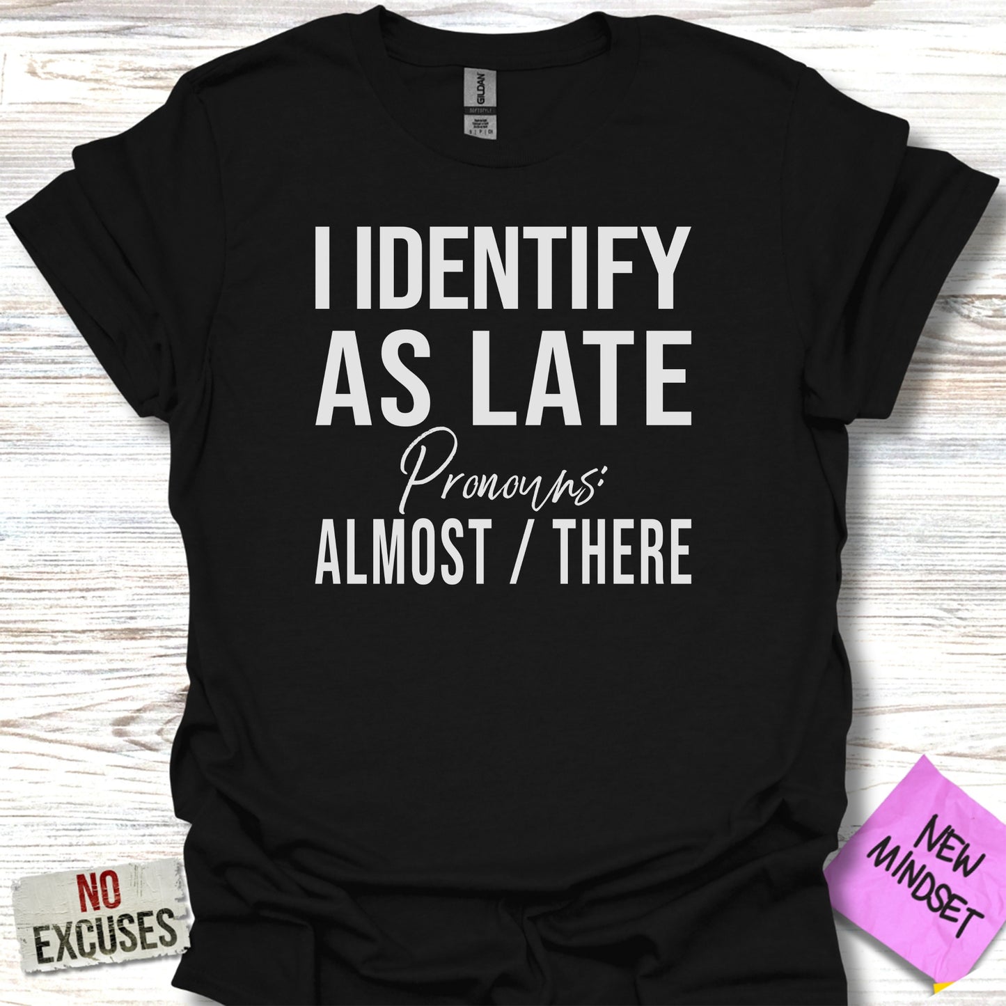 Black t-shirt with text "I IDENTIFY AS LATE Pronouns: ALMOST / THERE".