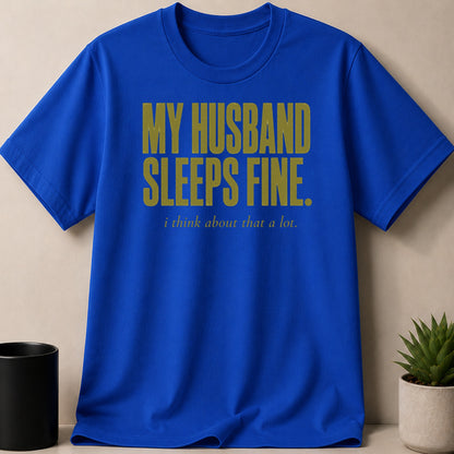 Blue t-shirt with gold text: "MY HUSBAND SLEEPS FINE. i think about that a lot."