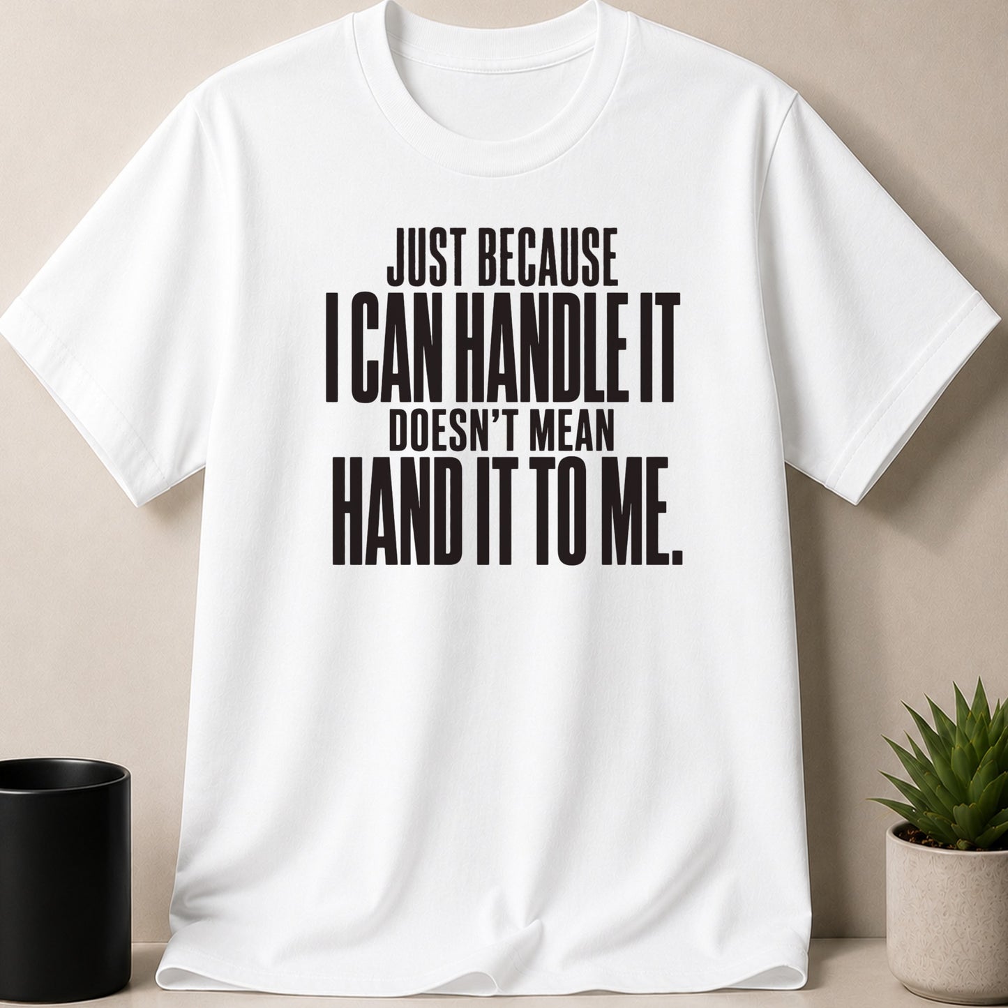 White t-shirt with black text reading "JUST BECAUSE I CAN HANDLE IT DOESN'T MEAN HAND IT TO ME."