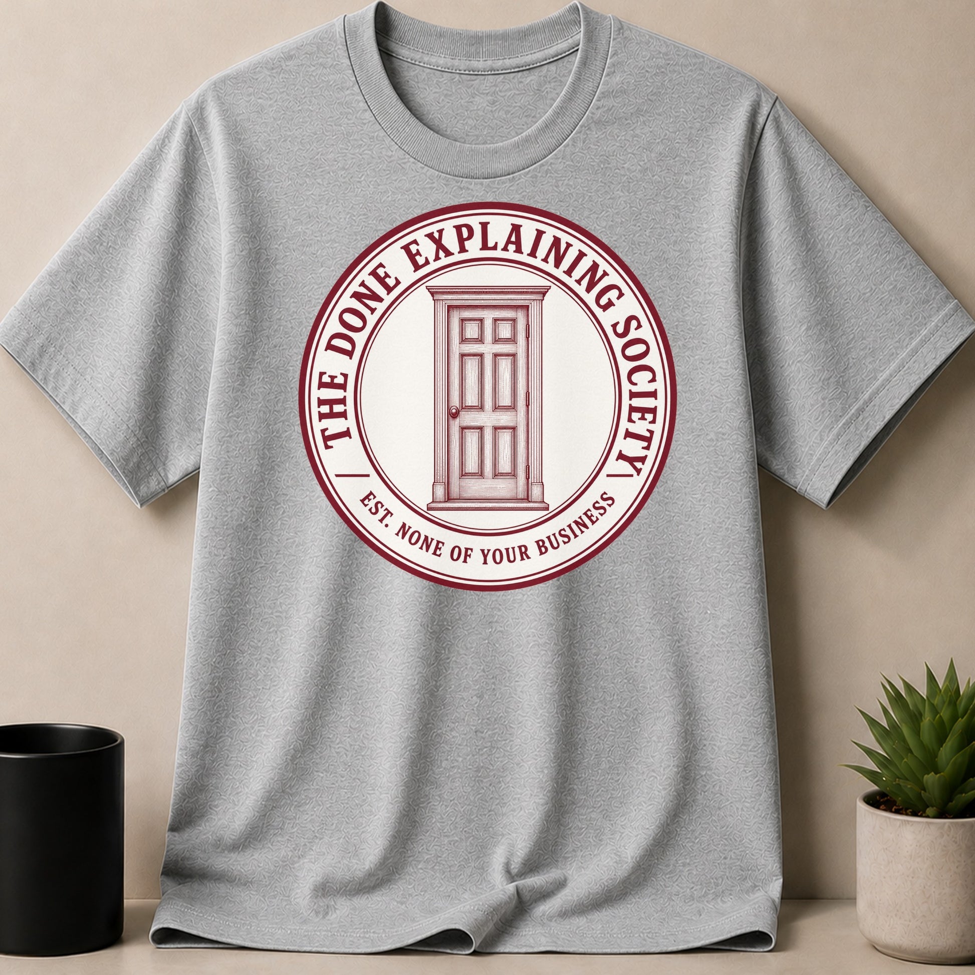 Grey t-shirt with a circular emblem featuring a door and text.
