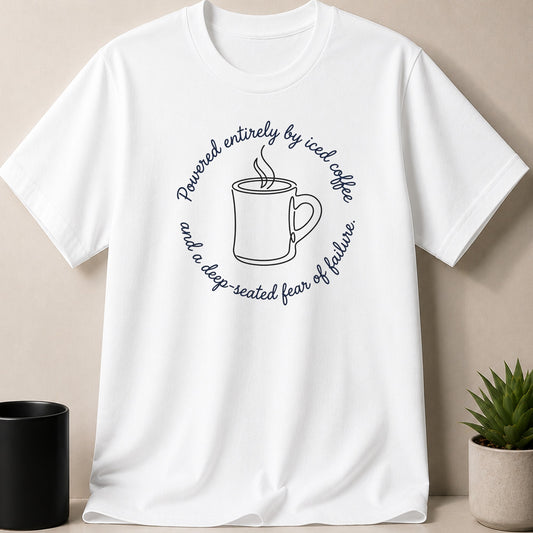 White t-shirt with circular text: "Powered entirely by iced coffee and a deep-seated fear of failure."