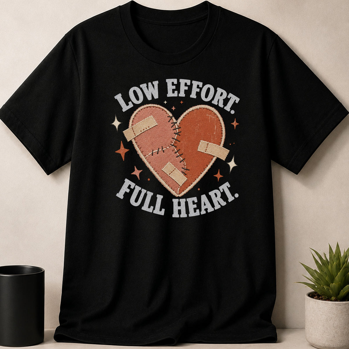 Black t-shirt with a stitched heart graphic and text "LOW EFFORT. FULL HEART."