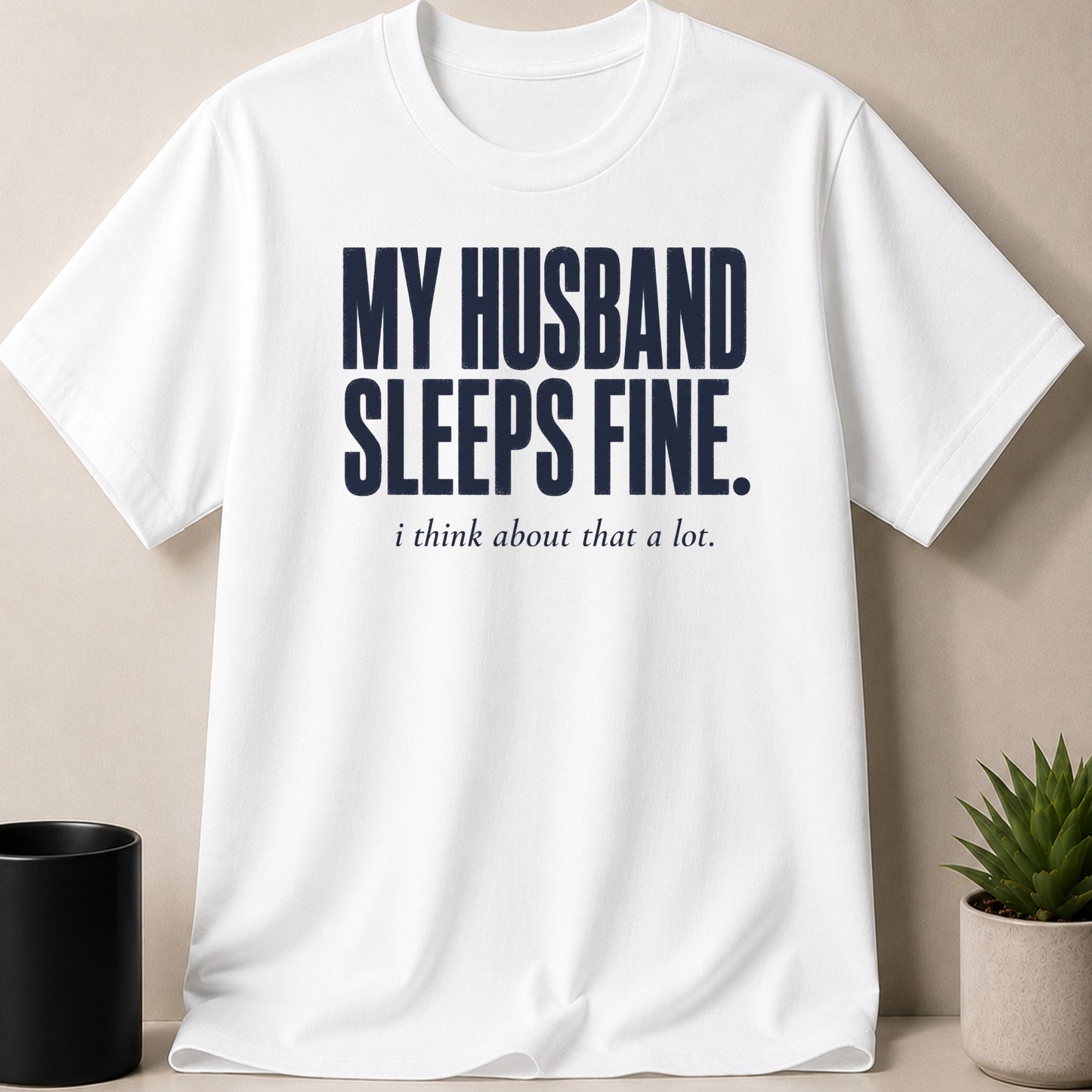 White t-shirt with navy text "MY HUSBAND SLEEPS FINE. i think about that a lot."