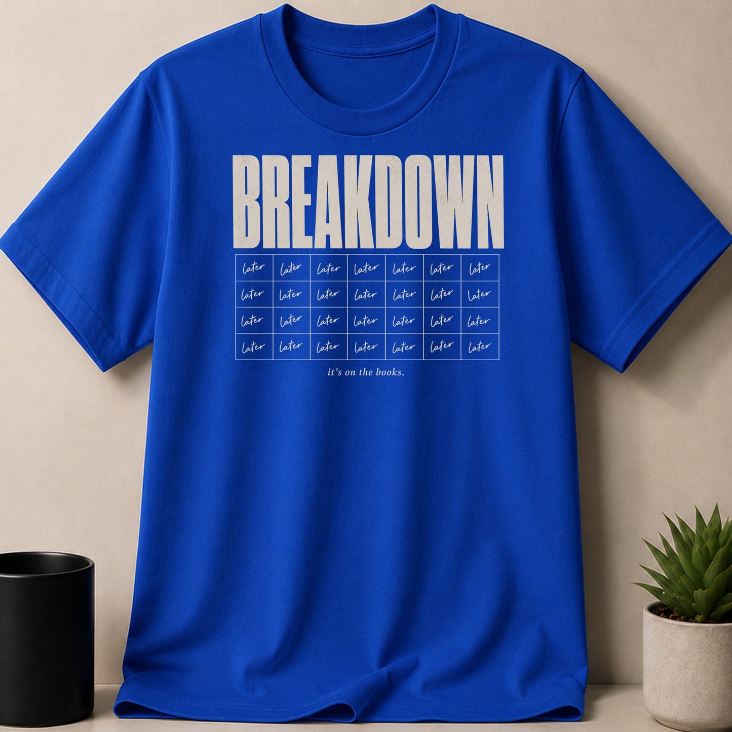 Royal blue t-shirt with "BREAKDOWN" and grid of "later" text.