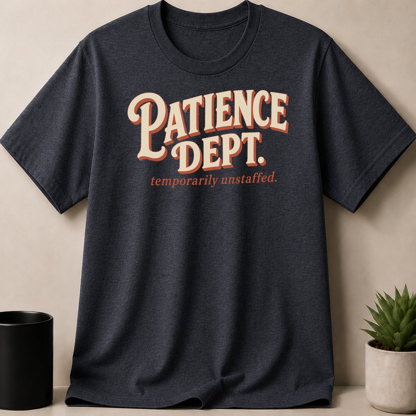 Dark grey t-shirt with "PATIENCE DEPT. temporarily unstaffed." text in cream and orange.