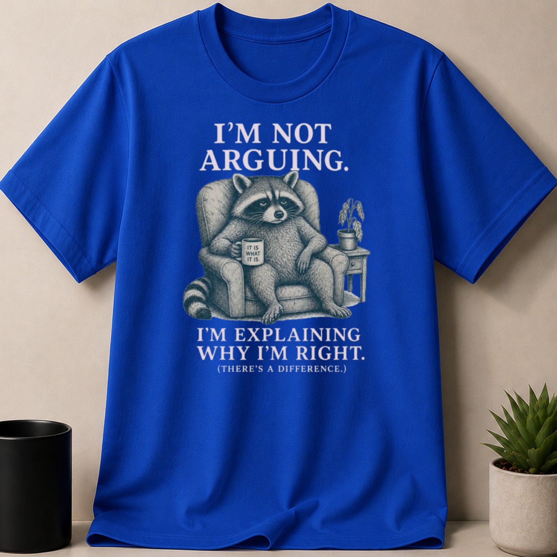 Royal blue t-shirt with raccoon graphic and text: "I'M NOT ARGUING. I'M EXPLAINING WHY I'M RIGHT."