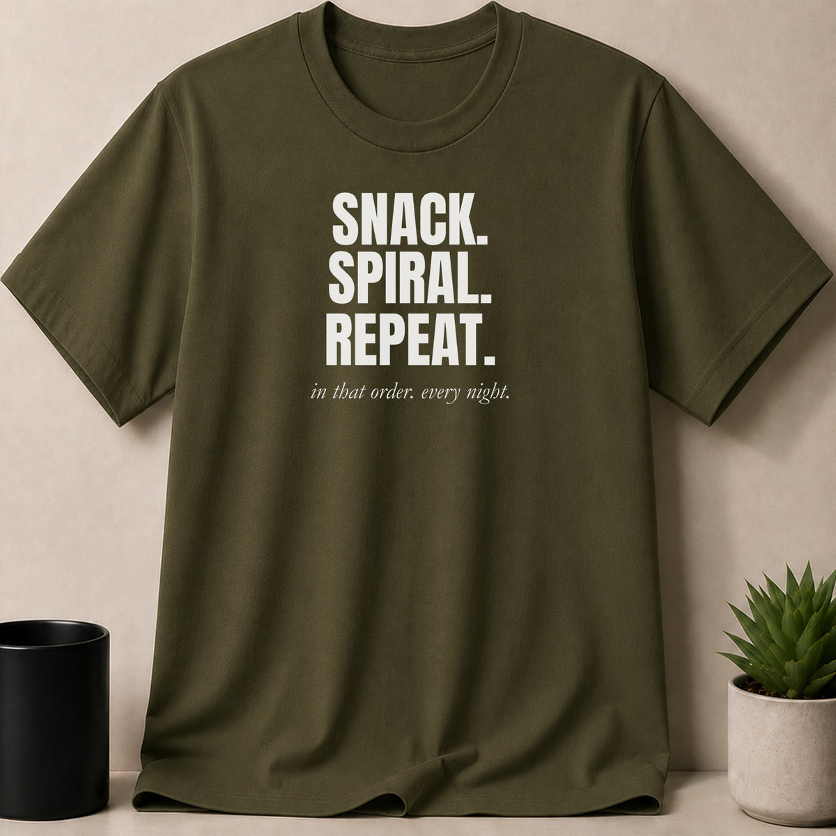 Olive green t-shirt with white text: SNACK. SPIRAL. REPEAT. in that order. every night.