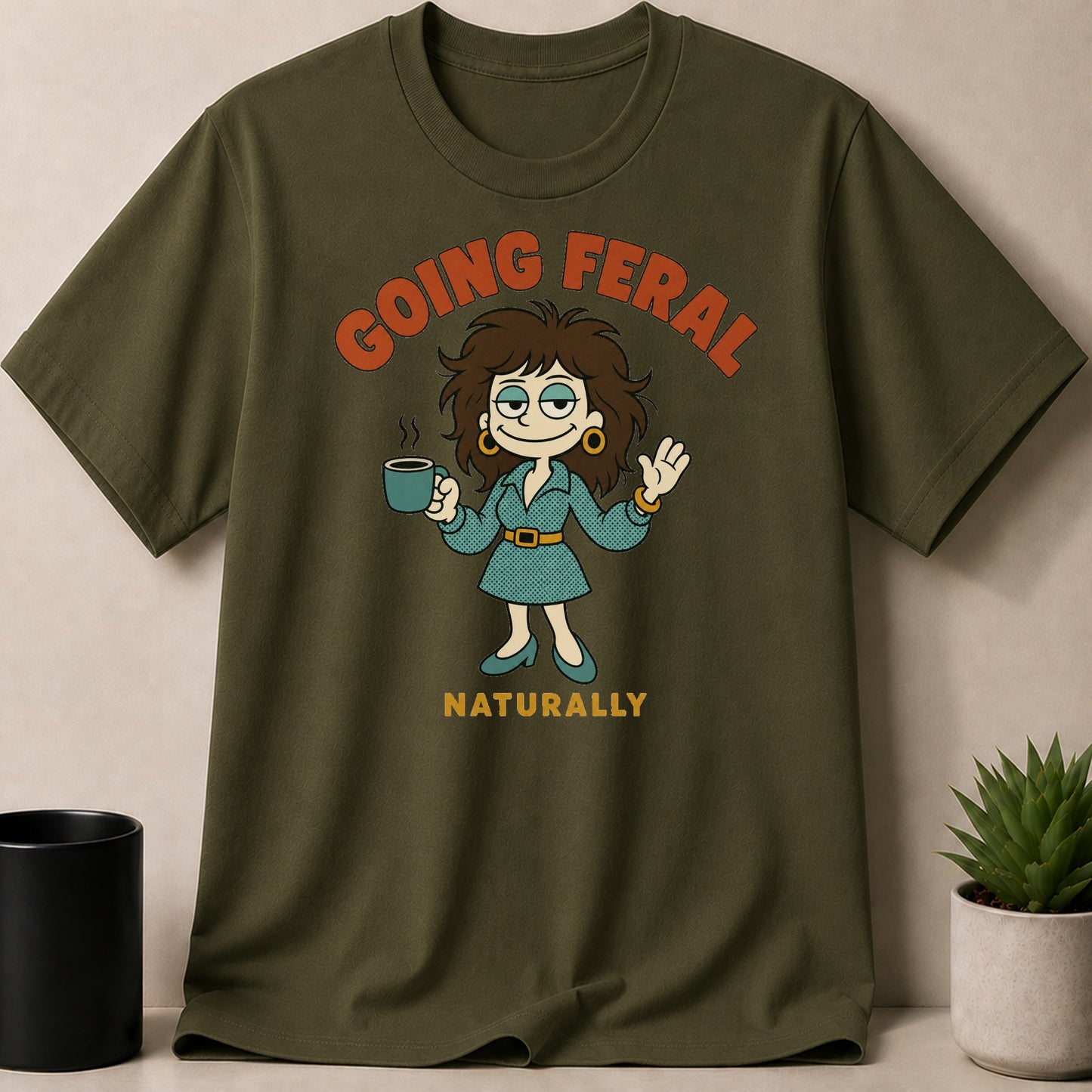 Olive green t-shirt with cartoon woman holding coffee, text "GOING FERAL NATURALLY".