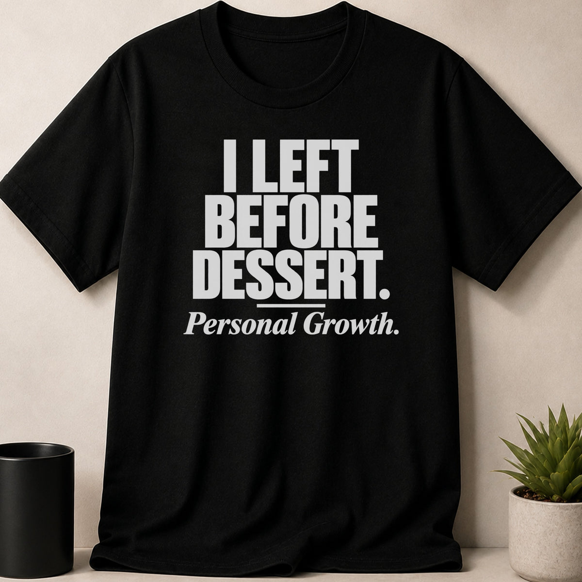 A black t-shirt printed with the white text, I LEFT BEFORE DESSERT. Personal Growth.