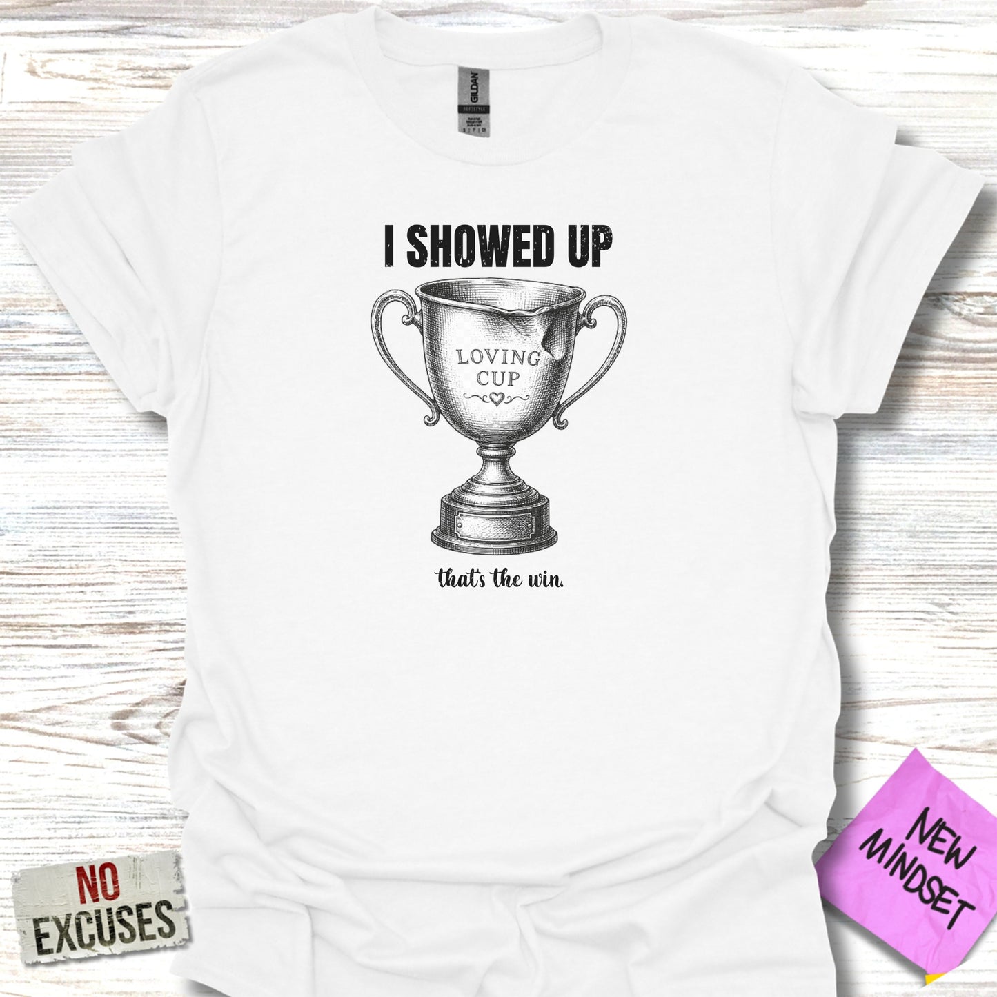White t-shirt with "I SHOWED UP LOVING CUP that's the win." text and trophy graphic.