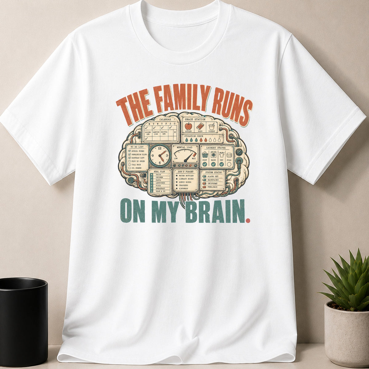 White t-shirt with "The family runs on my brain" graphic and brain icon with lists and gauges.