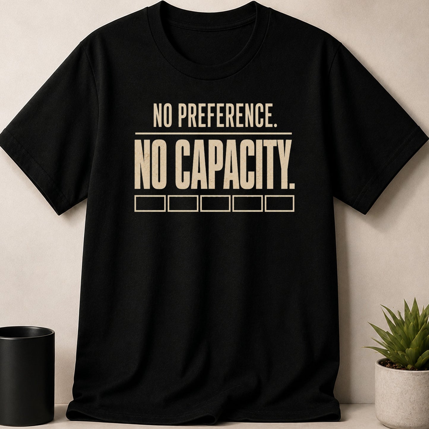 Black t-shirt with cream text "NO PREFERENCE. NO CAPACITY." and five empty boxes.