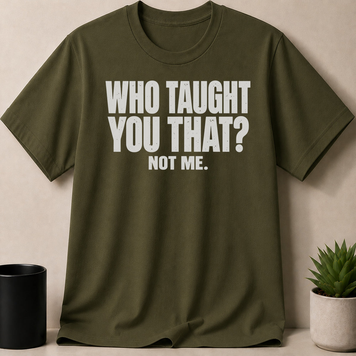 Olive green crew neck t-shirt with white distressed text reading WHO TAUGHT YOU THAT? NOT ME.
