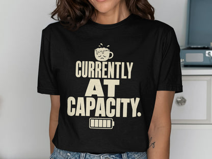 Black t-shirt with text "CURRENTLY AT CAPACITY" and a sad coffee cup and battery.