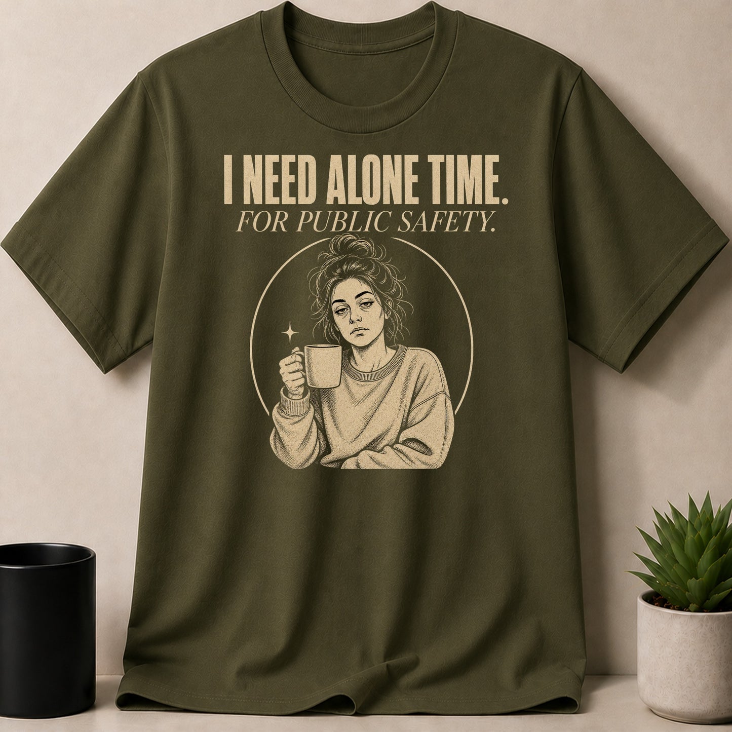 Olive green t-shirt with "I need alone time. For public safety." text and woman with coffee illustration.