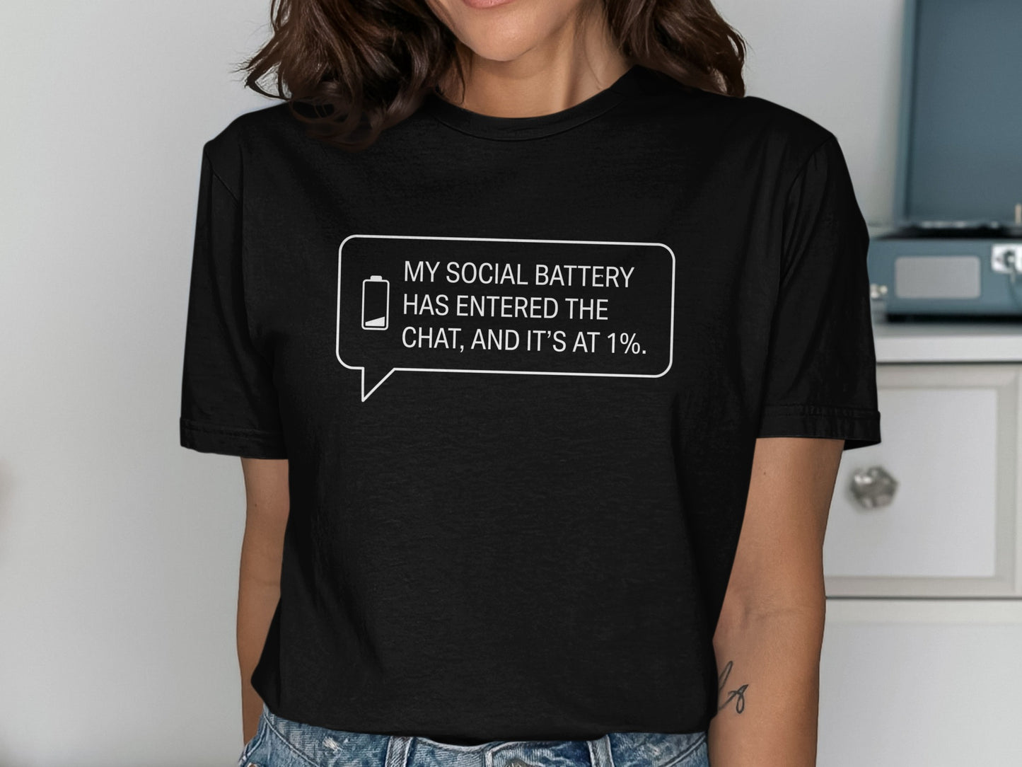 Black t-shirt with text bubble: "MY SOCIAL BATTERY HAS ENTERED THE CHAT, AND IT'S AT 1%."