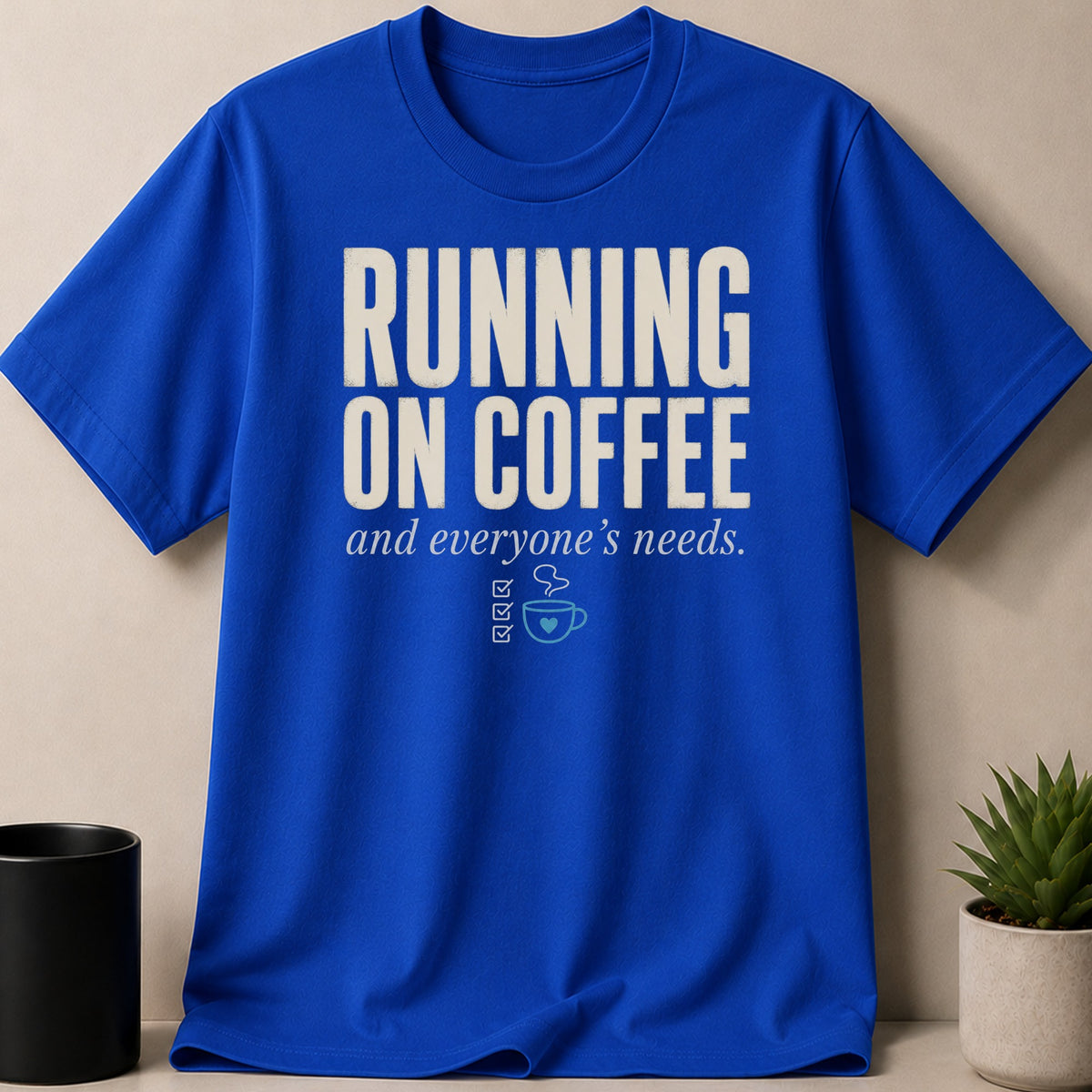 Royal blue t-shirt with "Running on coffee and everyone's needs" text and coffee cup graphic.